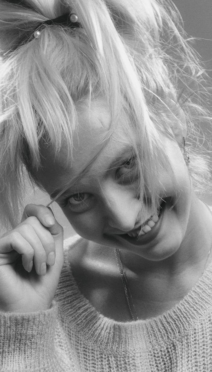 Joyful close-up headshot of a smiling woman in grayscale, emphasizing her playful expression.