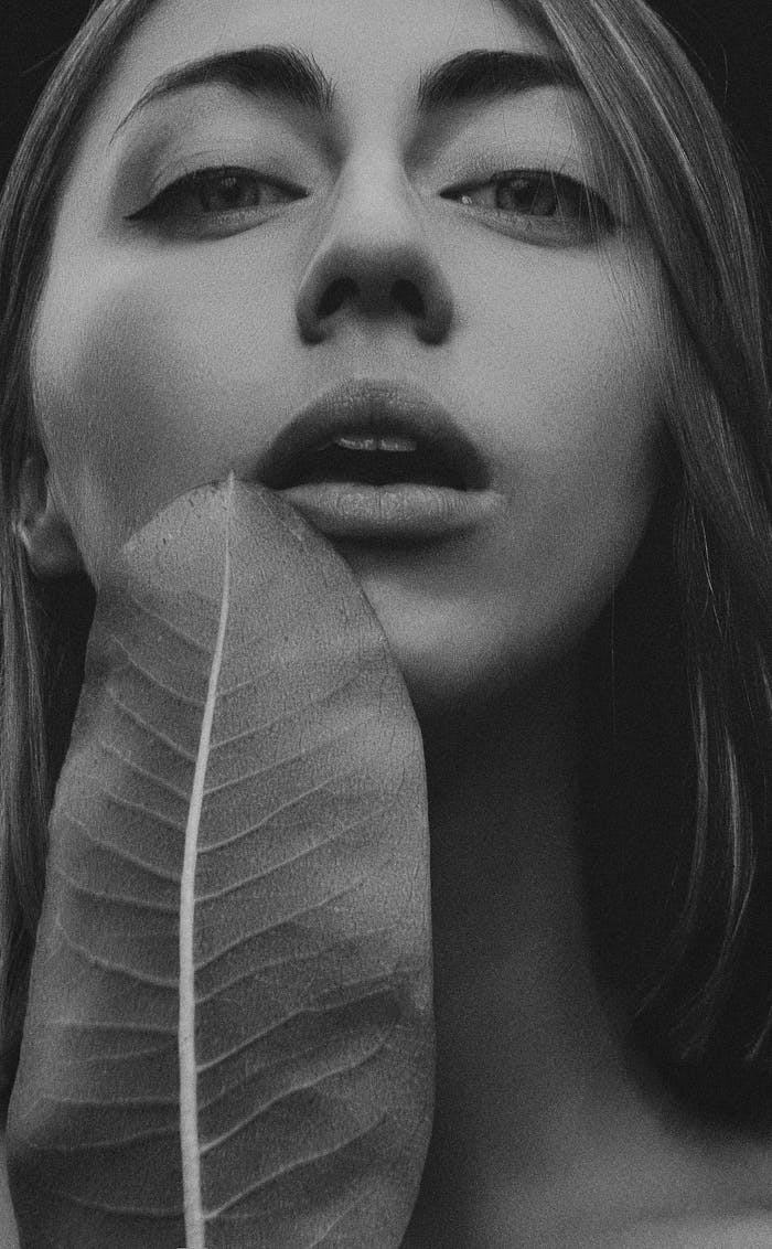 about-01 Artistic black and white portrait of a woman holding a leaf, emphasizing natural beauty.